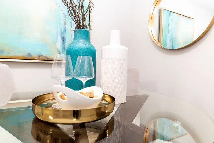Elegant dining setup featuring a modern glass table, chic turquoise and white vases, and tasteful decor accents.