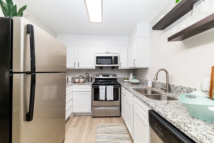 Modern kitchen with sleek stainless steel appliances, elegant white cabinetry, and granite countertops, perfect for culinary creativity.