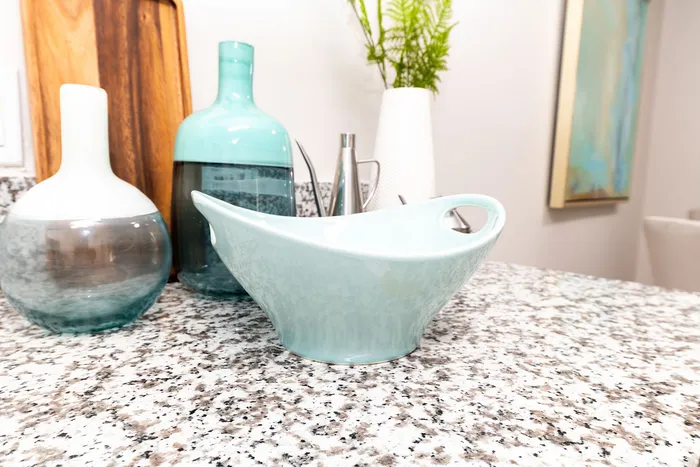 Elegant kitchen countertop with stylish blue and white ceramic decor, featuring modern vases and a sleek cutting board.