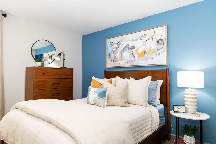Charming bedroom with elegant wooden furniture, vibrant blue accent wall, and cozy bedding for a peaceful retreat.