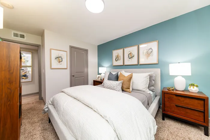 Inviting bedroom with modern decor, featuring a cozy bed, stylish artwork, and elegant bedside tables with warm lighting.