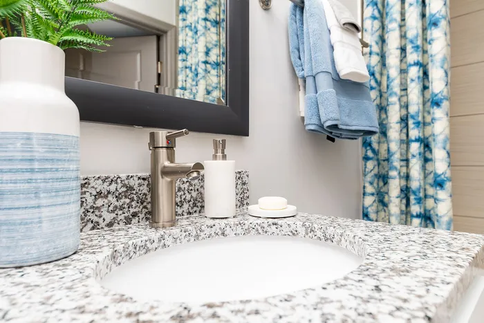 Elegant bathroom vanity with sleek granite countertop and modern fixtures, complemented by stylish blue decor.