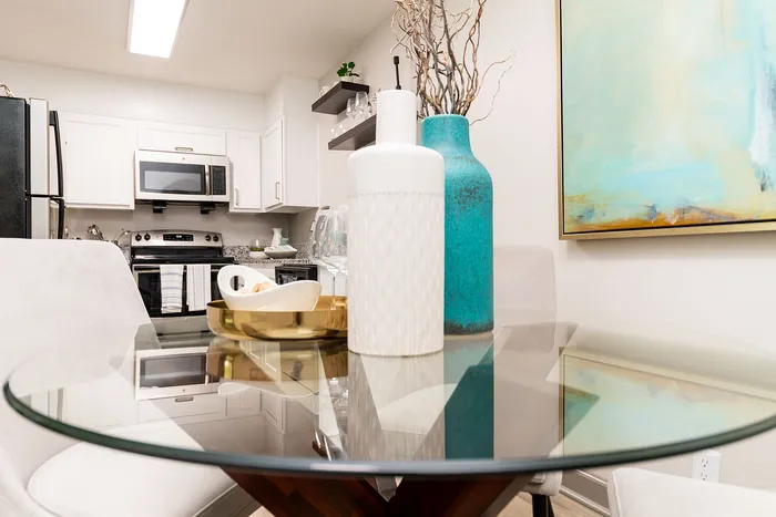Chic modern kitchen and dining area featuring sleek appliances, elegant decor, and a stylish glass table.