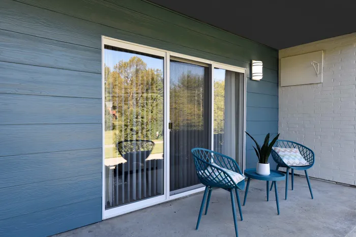 Charming apartment balcony with cozy seating, modern blue decor, and serene view.