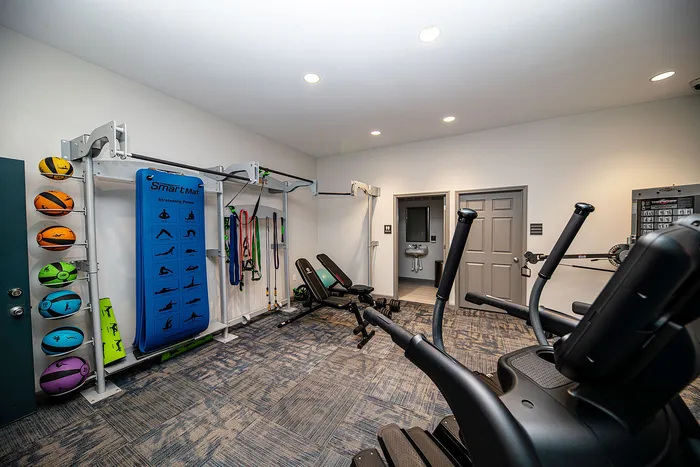 Modern fitness room with exercise equipment, colorful medicine balls, and a stretching area, ideal for an active lifestyle.