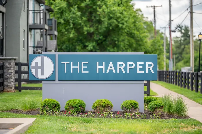 Charming view of The Harper's welcoming entrance sign, nestled among lush greenery and stylish architecture.
