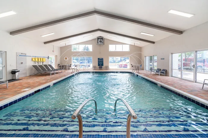 Inviting indoor pool with elegant water features and ample natural light, perfect for relaxation and leisure.