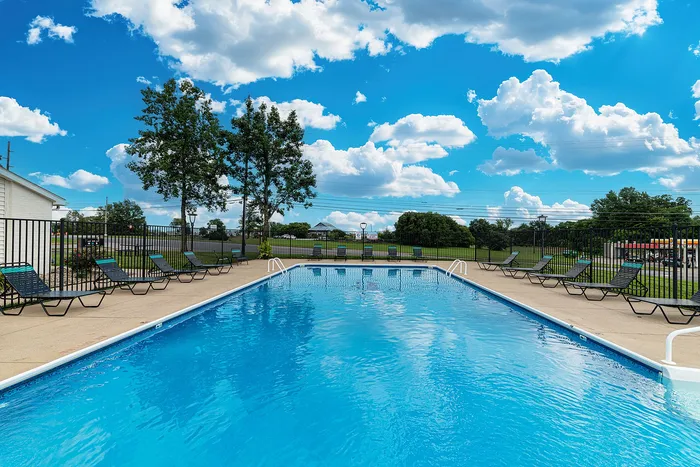 Inviting outdoor swimming pool with comfortable lounge chairs and vibrant blue sky, perfect for relaxation and enjoyment.