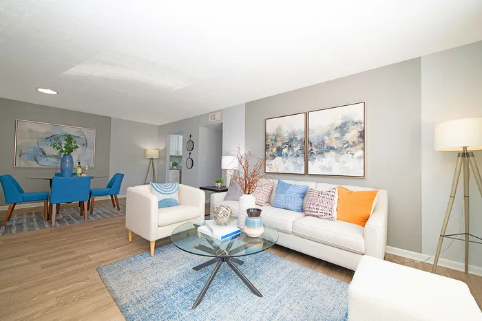 Bright and modern living area with stylish decor, featuring a cozy white sofa, vibrant blue accents, and elegant wall art.
