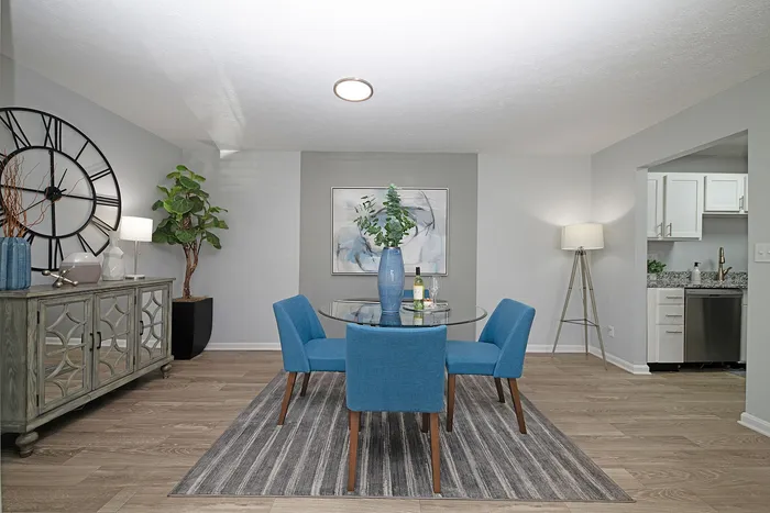 Elegant dining area with modern blue chairs, stylish glass table, and contemporary d&eacute;cor in a cozy, open-concept apartment.