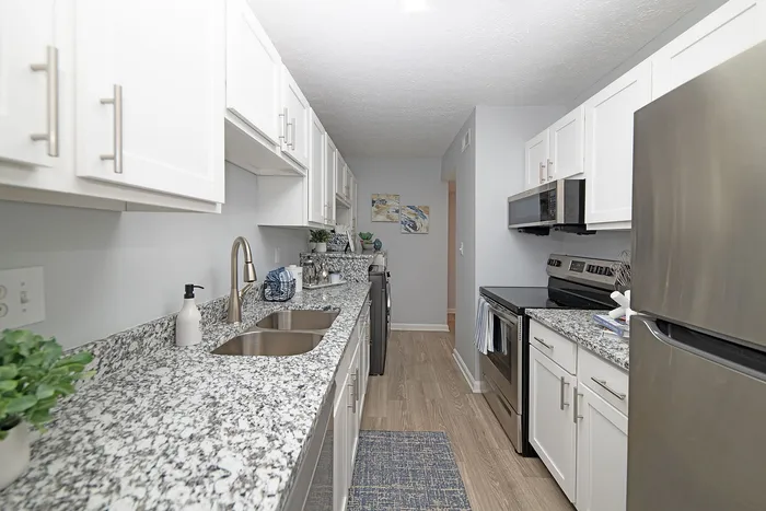 Modern kitchen with elegant granite countertops, stainless steel appliances, and ample white cabinetry, creating a sleek and inviting culinary space.