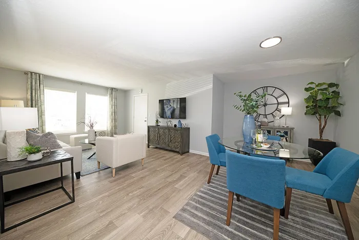 Bright and modern open-concept living room with stylish blue dining set, elegant decor, and abundant natural light.