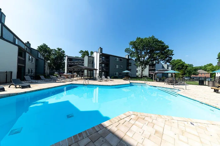 Inviting outdoor swimming pool area surrounded by modern apartment buildings and lush greenery, perfect for relaxation and leisure.