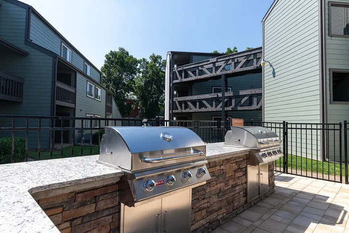 Inviting outdoor grilling area featuring modern stainless-steel BBQ stations with charming apartment buildings in the background.