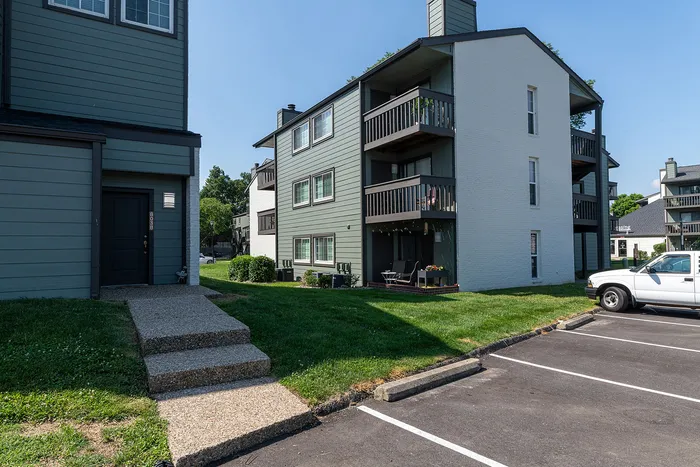 Charming apartment building with classic architecture, featuring spacious balconies, surrounded by lush greenery and ample parking space.