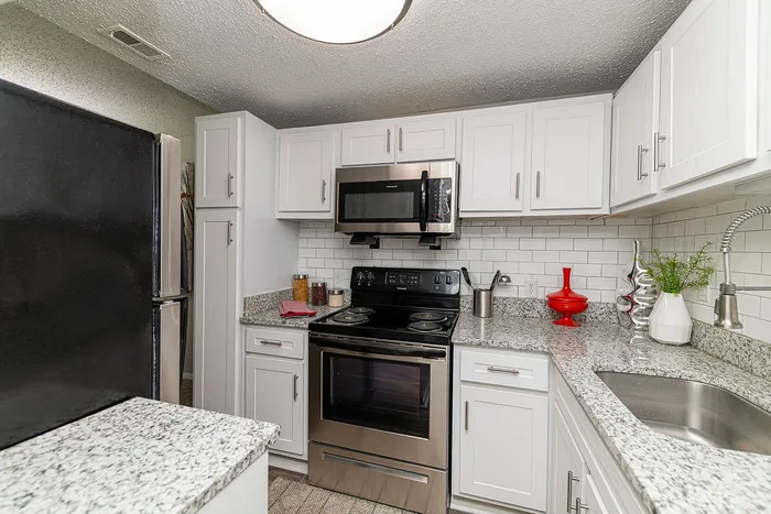 Modern kitchen with sleek granite countertops, stainless steel appliances, and chic white cabinetry.