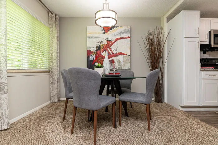 Contemporary dining area with a glass-top table, elegant gray chairs, and modern art adding a touch of sophistication.