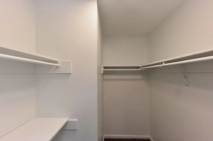 Spacious walk-in closet with built-in shelving and ample hanging space, perfect for organized living.