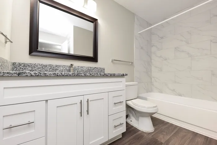 Modern bathroom featuring sleek white cabinetry, granite countertop, and elegant tiled walls with a luxurious bathtub.