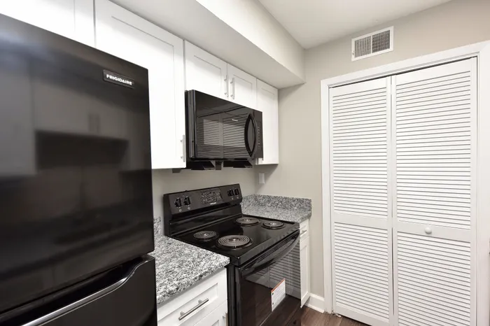 Modern kitchen with sleek black appliances, granite countertops, and crisp white cabinetry for a clean, contemporary look.