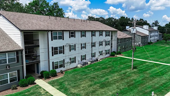 Charming apartment complex with modern design and lush green lawns under a bright blue sky.