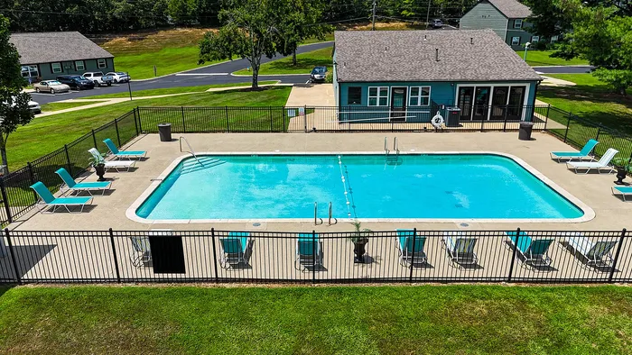 Inviting outdoor pool area with elegant lounge chairs, perfect for relaxation and summer enjoyment, nestled within a vibrant residential community.