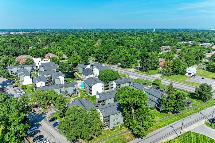 Scenic aerial view of a vibrant apartment community surrounded by lush green landscapes, offering a serene and inviting neighborhood atmosphere.