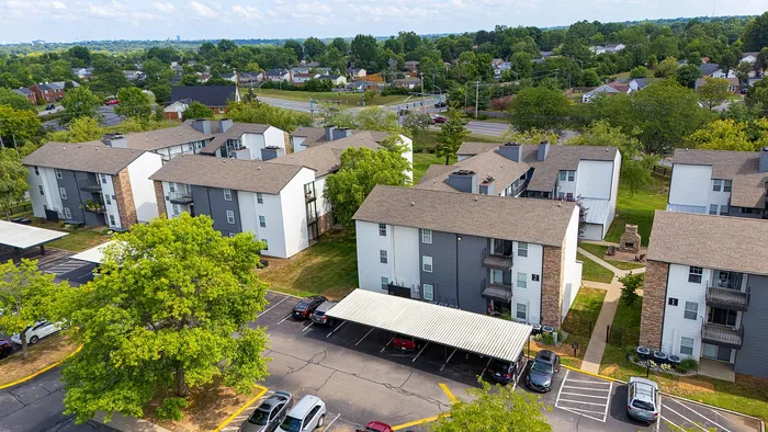 Aerial view of charming apartment complex surrounded by lush greenery and modern amenities, featuring spacious balconies and ample parking in a serene neighborhood setting.