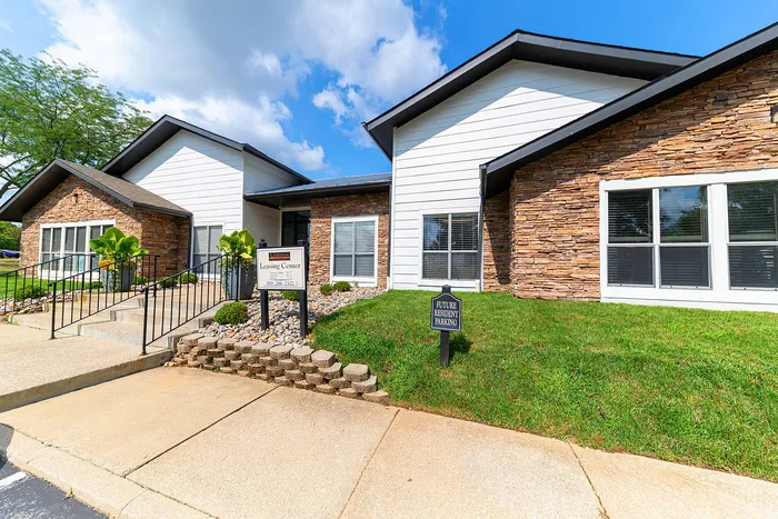 Charming leasing center with a modern stone exterior, surrounded by manicured landscaping and bright blue skies.