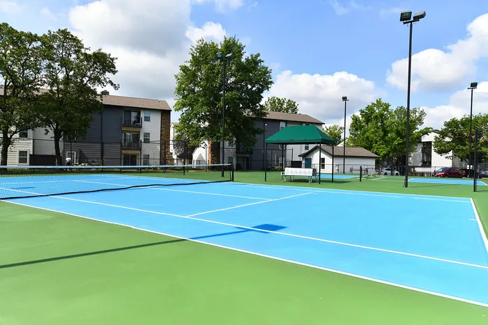 Vibrant apartment complex with spacious tennis courts surrounded by lush greenery, perfect for active living.