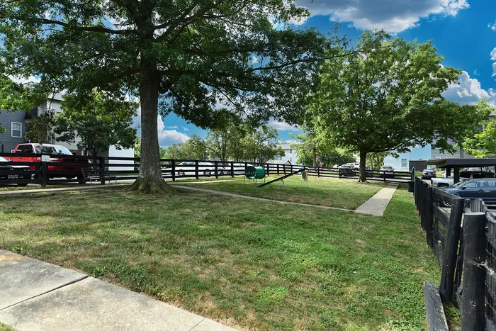 Charming outdoor space with lush green lawn, mature trees, and a fenced pathway, perfect for relaxing and enjoying nature.