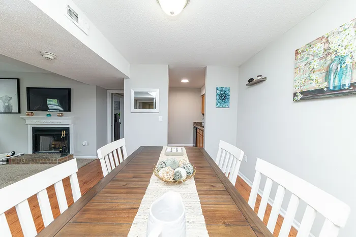 Inviting dining area with a stylish wooden table, elegant decor, and view of a cozy living space with a modern fireplace.