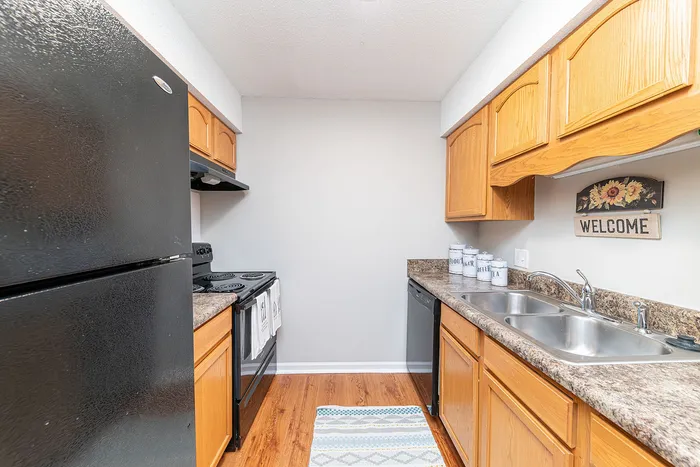 Cozy kitchen with modern black appliances, warm wooden cabinetry, and stylish granite countertops, offering a welcoming and functional space.