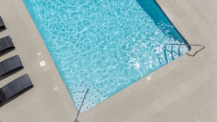 Inviting outdoor swimming pool with sparkling blue water and comfortable poolside lounge chairs, perfect for relaxation and leisure.
