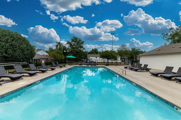 Luxurious outdoor swimming pool with lounge chairs under a vibrant blue sky, perfect for relaxation and sunbathing.