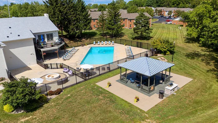 Inviting outdoor pool area with a modern clubhouse, surrounded by lush greenery and ample seating, perfect for relaxation and leisure.
