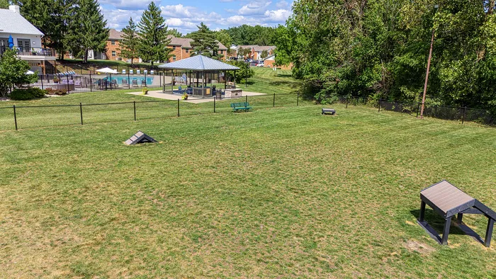 Expansive fenced green space with modern gazebo and pool in a vibrant community setting, perfect for outdoor relaxation and activities.