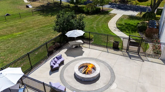 Charming outdoor patio with cozy fire pit, surrounded by elegant seating and lush green lawn, perfect for relaxation and entertainment.