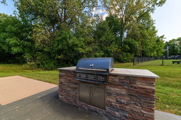 Modern outdoor barbecue area with a sleek grill surrounded by lush greenery, perfect for entertaining.