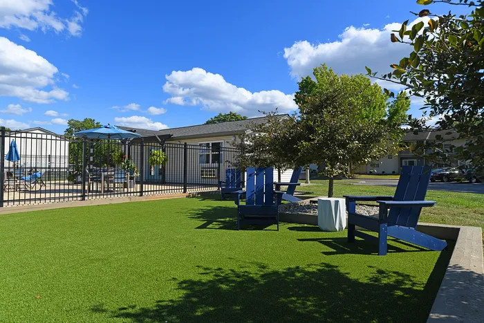 Charming outdoor seating area with vibrant blue chairs and lush greenery, perfect for relaxation under the sunny sky.