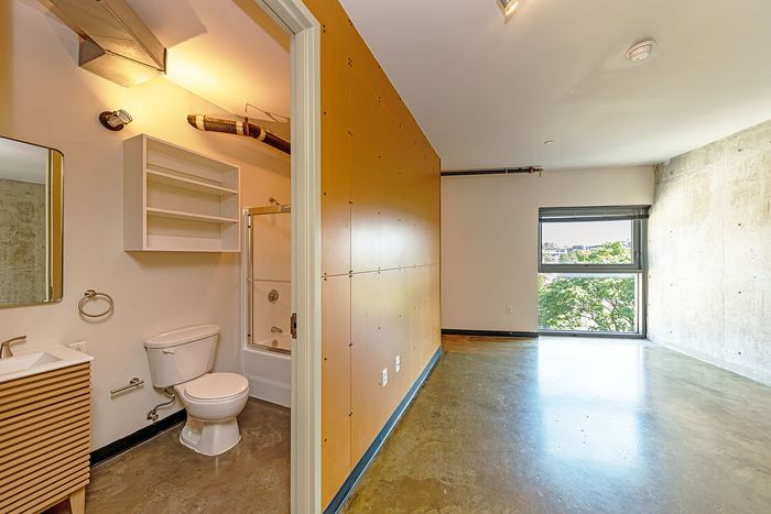 Modern apartment interior featuring a sleek bathroom with stylish fixtures and a bright, spacious room with a large window offering natural light.