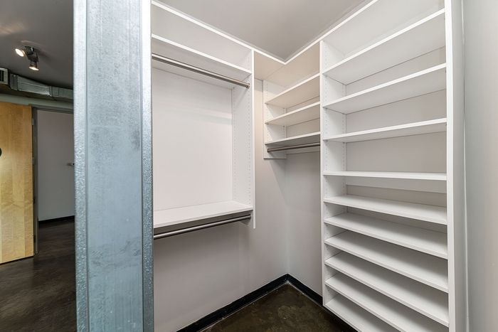 Spacious walk-in closet with sleek white shelving and ample storage space.