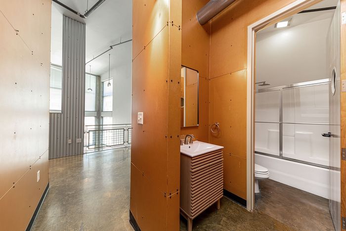 Contemporary industrial-style loft with high ceilings, modern bathroom, and polished concrete floors offering a sleek and urban living space.