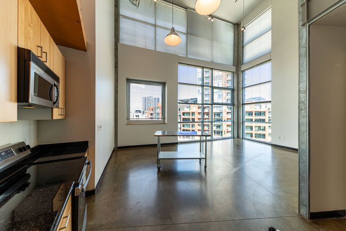 Bright modern apartment showcasing an open layout with high ceilings, large windows, and a sleek kitchen design.