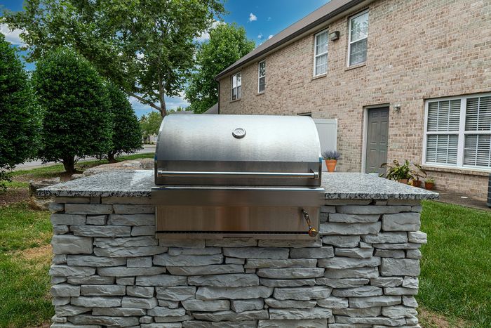 Charming outdoor stone grill station beneath a clear sky, perfect for summer BBQs and entertaining.