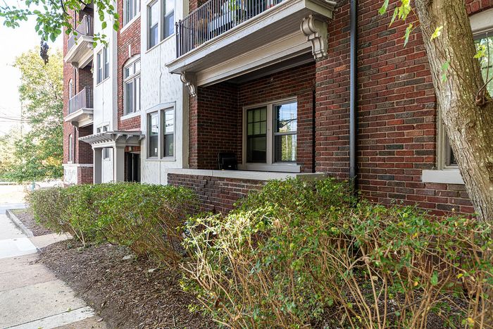 Charming brick apartment building with elegant balconies and lush greenery, offering a peaceful and inviting atmosphere.