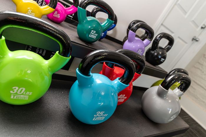 Vibrant array of kettlebells in various weights, perfectly arranged on gym shelves, ready for a dynamic workout session.