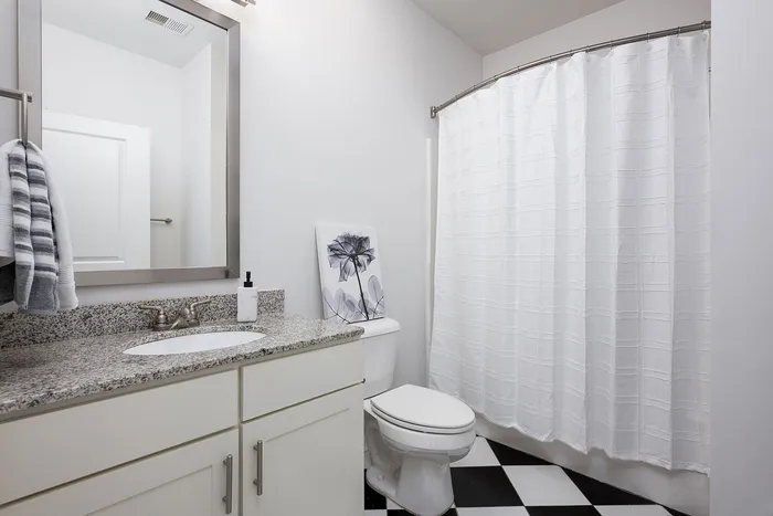 Modern bathroom with sleek granite countertop, elegant fixtures, and stylish black and white tile flooring.
