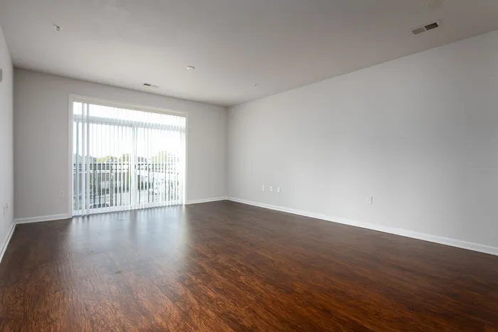 Bright and spacious living area with elegant hardwood flooring and large windows for ample natural light.