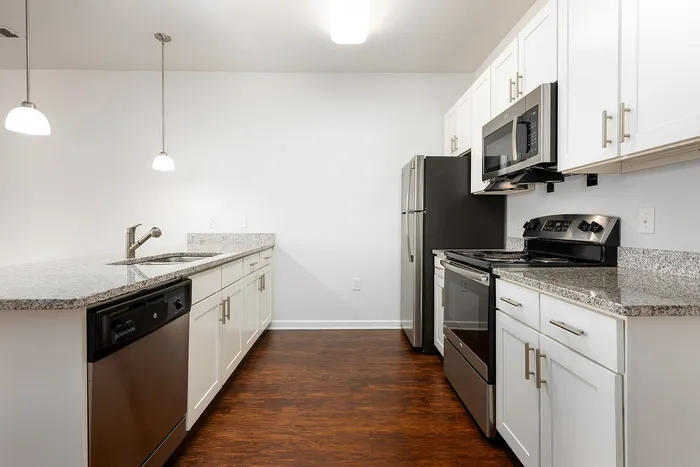 Sleek modern kitchen with granite countertops, stainless steel appliances, and elegant white cabinetry.